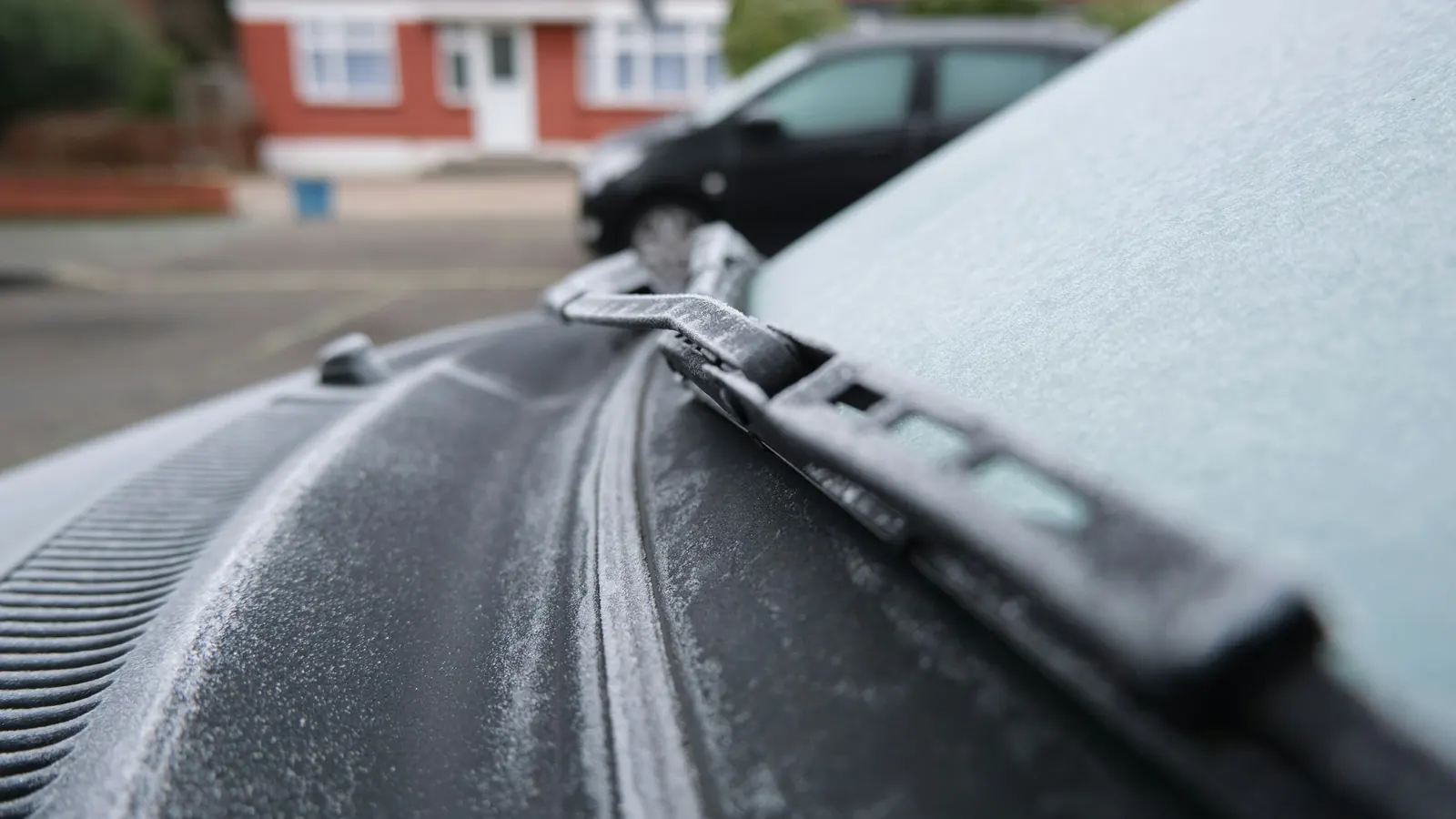 Frost on a car's hood and windshield wiper on a cold morning