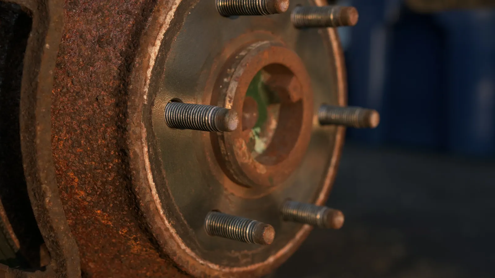 A rusty brake rotor and wheel hub with the wheel removed and the lug studs showing